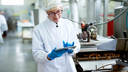 A woman wearing a white lab coat is engaged with a tablet, showcasing her work in a laboratory environment.